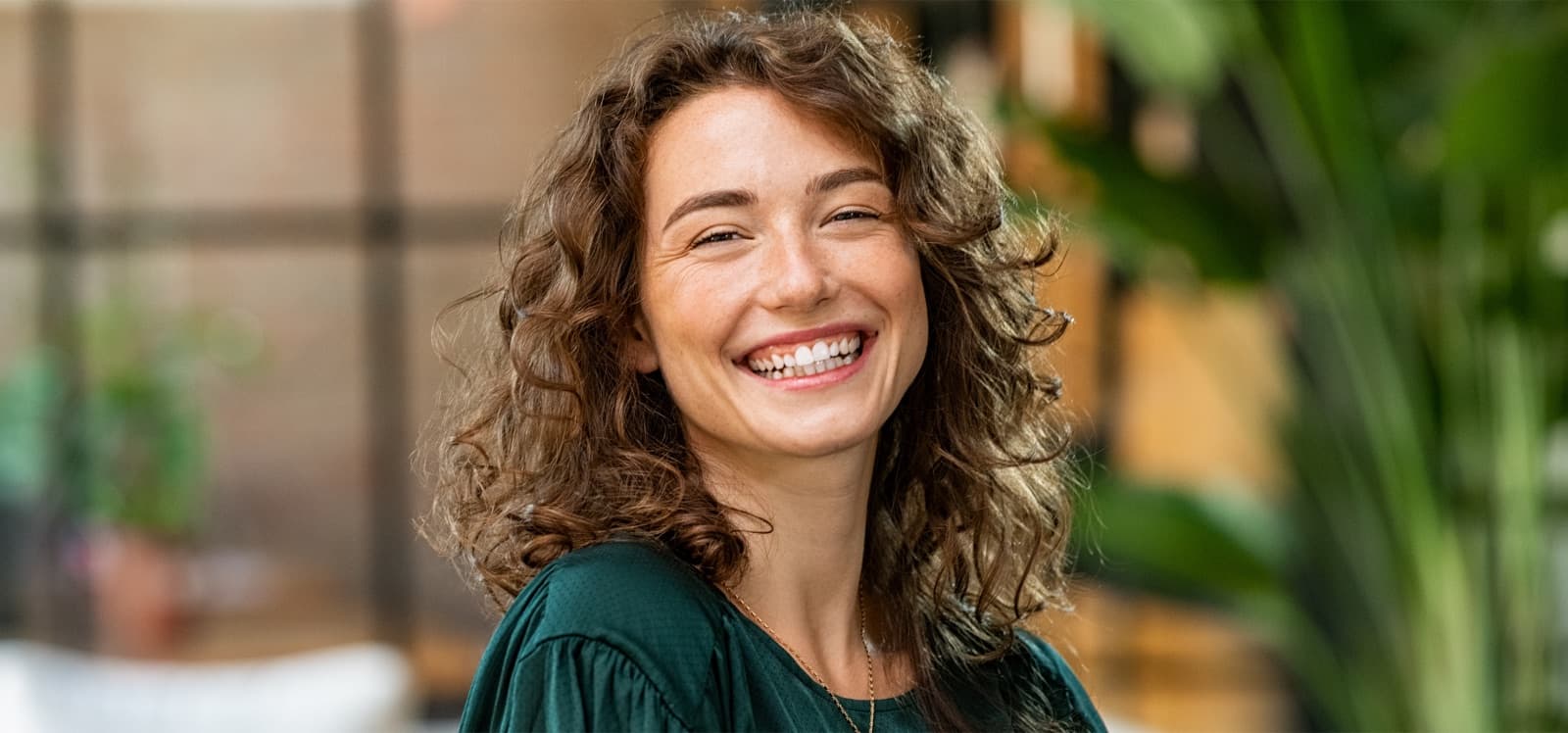Mujer sonriente de cabello rizado en un entorno exterior
