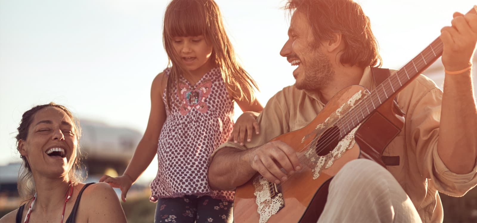 Familia feliz al aire libre, padre tocando guitarra