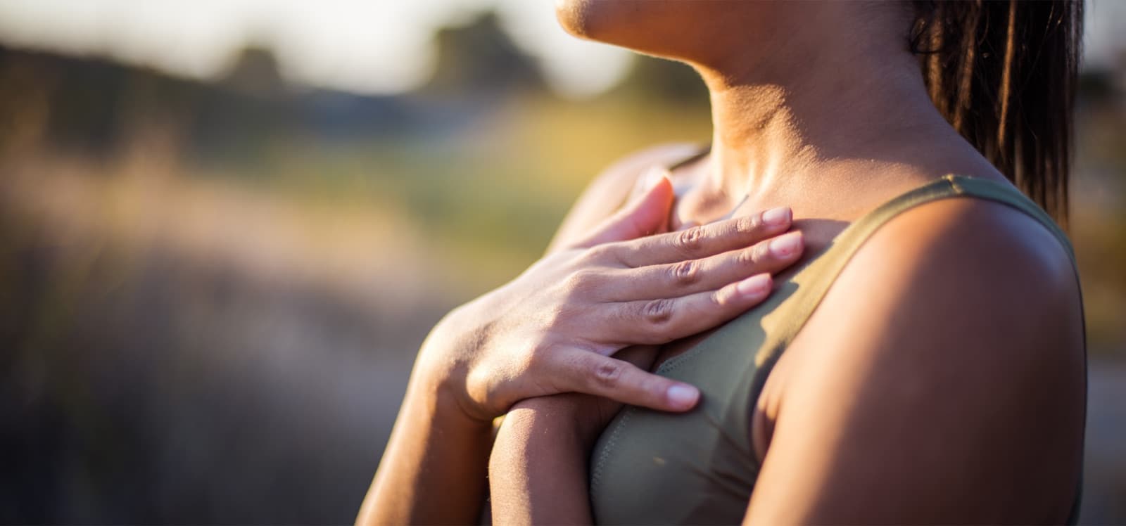 Mujer con la mano sobre el pecho, luz cálida de atardecer