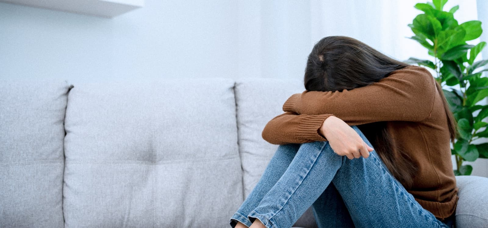 Mujer sentada en un sofá abrazando sus rodillas