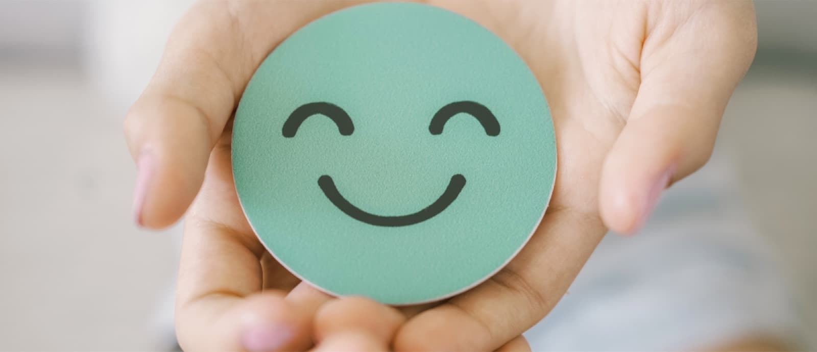 Manos sosteniendo una carita sonriente, símbolo de bienestar emocional
