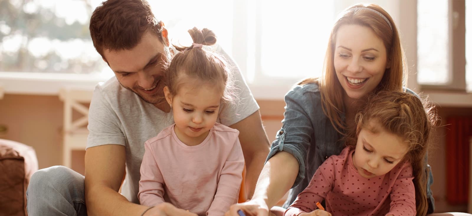 Padre con dos niñas pequeñas mirando algo juntos en interior