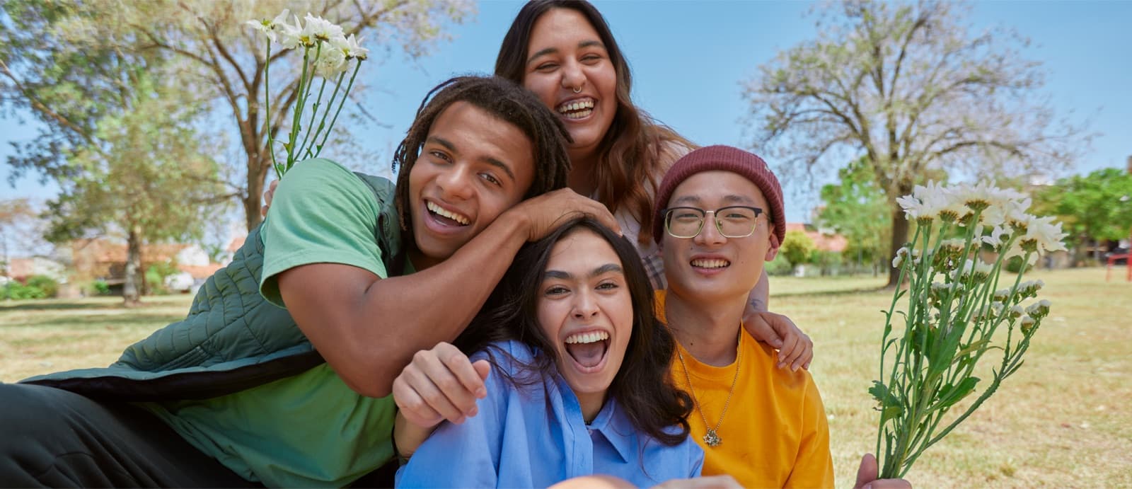 Grupo de jóvenes amigos abrazados riendo al aire libre