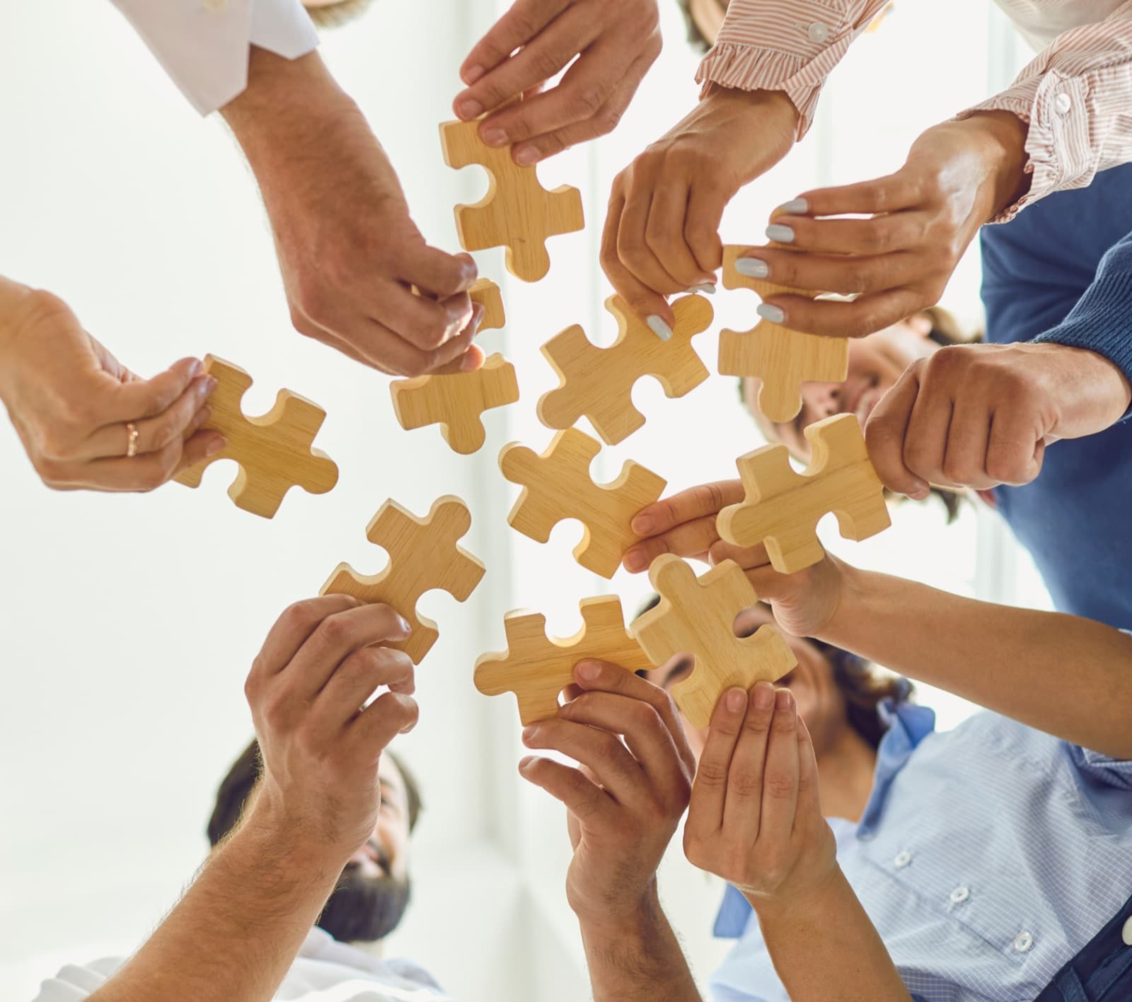 Manos de un equipo ensamblando piezas de un rompecabezas