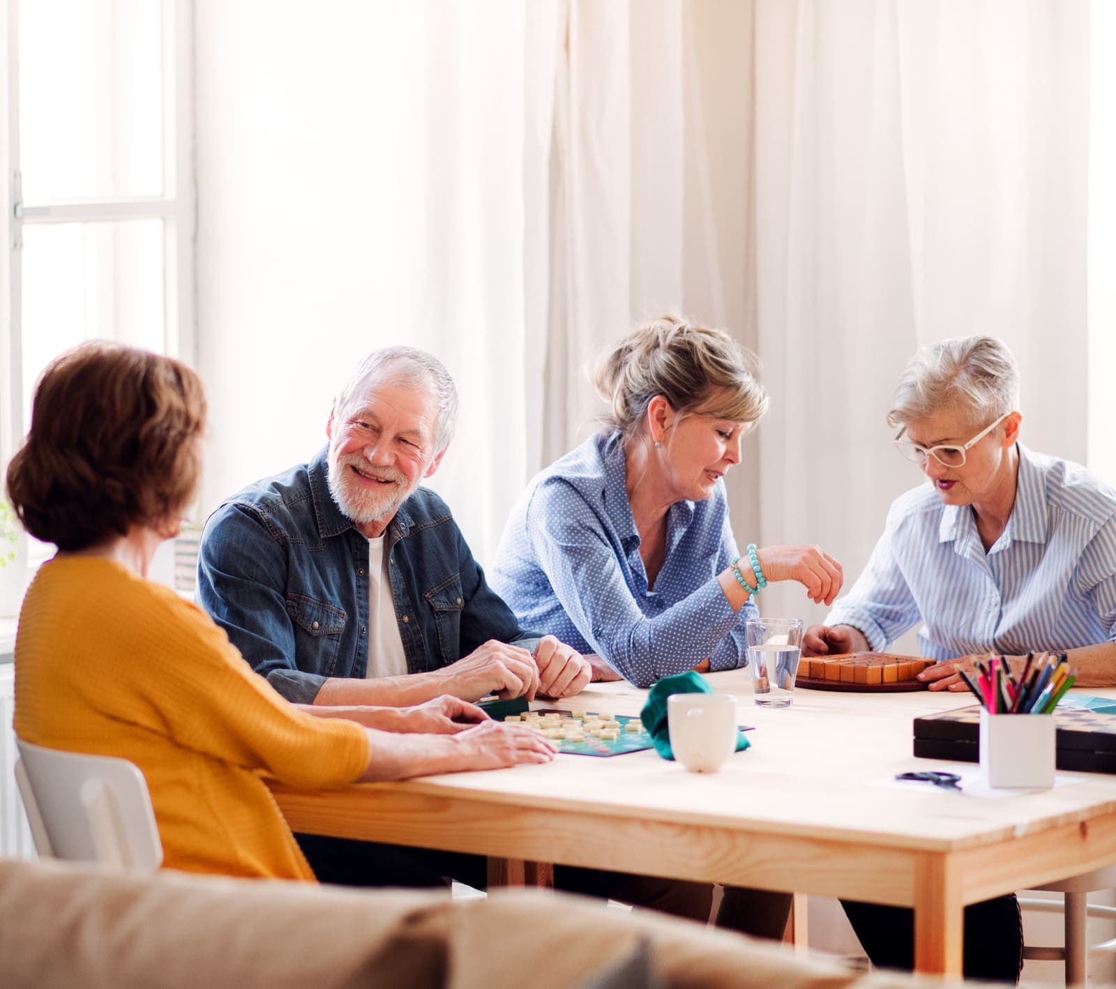Grupo de adultos mayores compartiendo un juego de mesa alrededor de una mesa